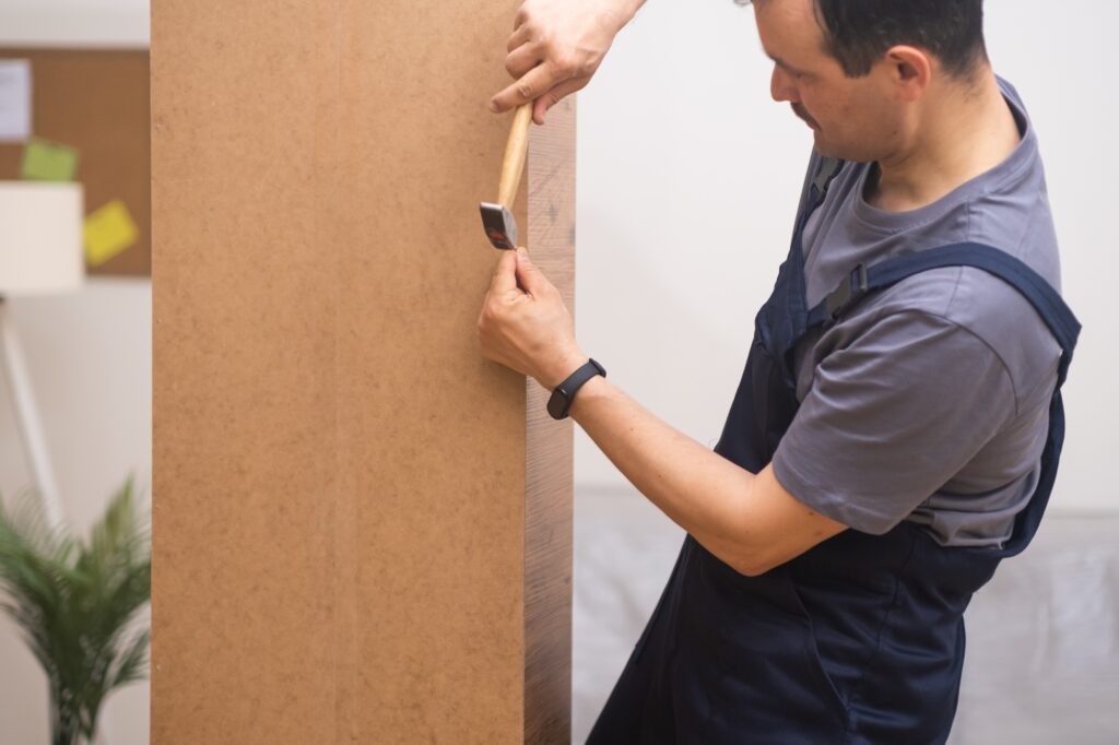 Managing furniture assembling business man hammering nail into furniture